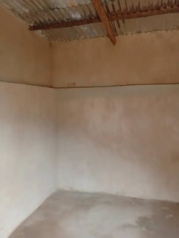 A newly plastered room with a corrugated metal roof, ready to be fitted out